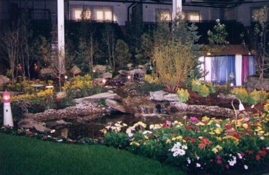A garden display with a pond, waterfall, flowers, and a small lighthouse.