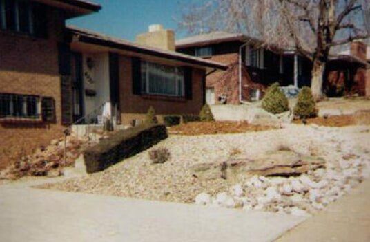 Suburban home with gravel landscaping, including rocks and small evergreen trees.