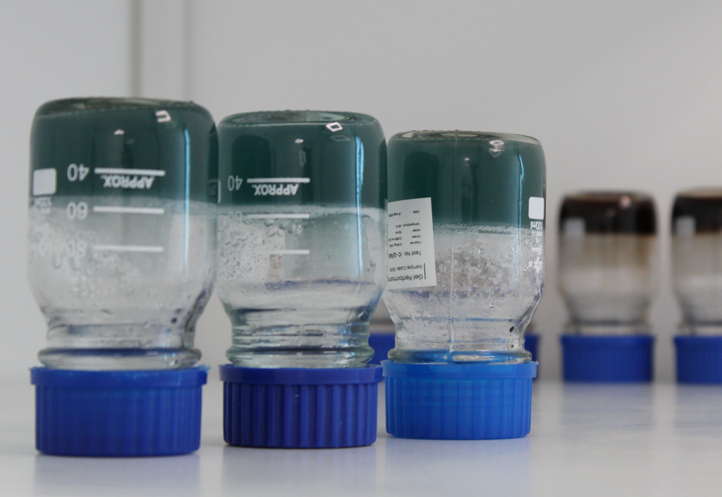 A row of bottles with blue lids are lined up on a table.