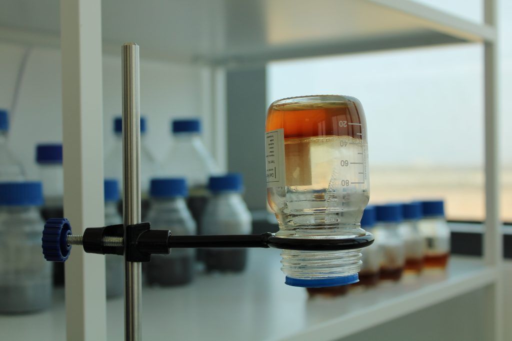 A bottle of liquid is sitting on a clamp in a laboratory.