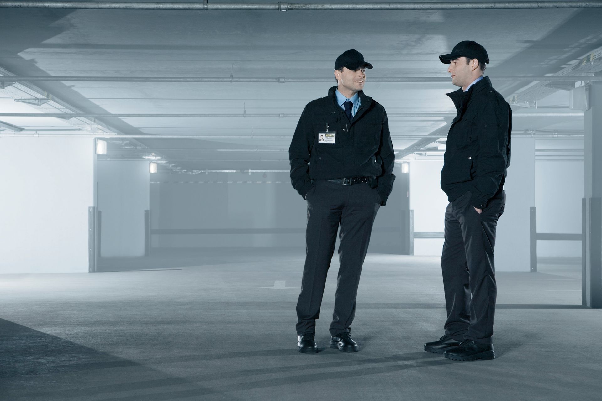 Two security guards are standing next to each other in a parking garage.
