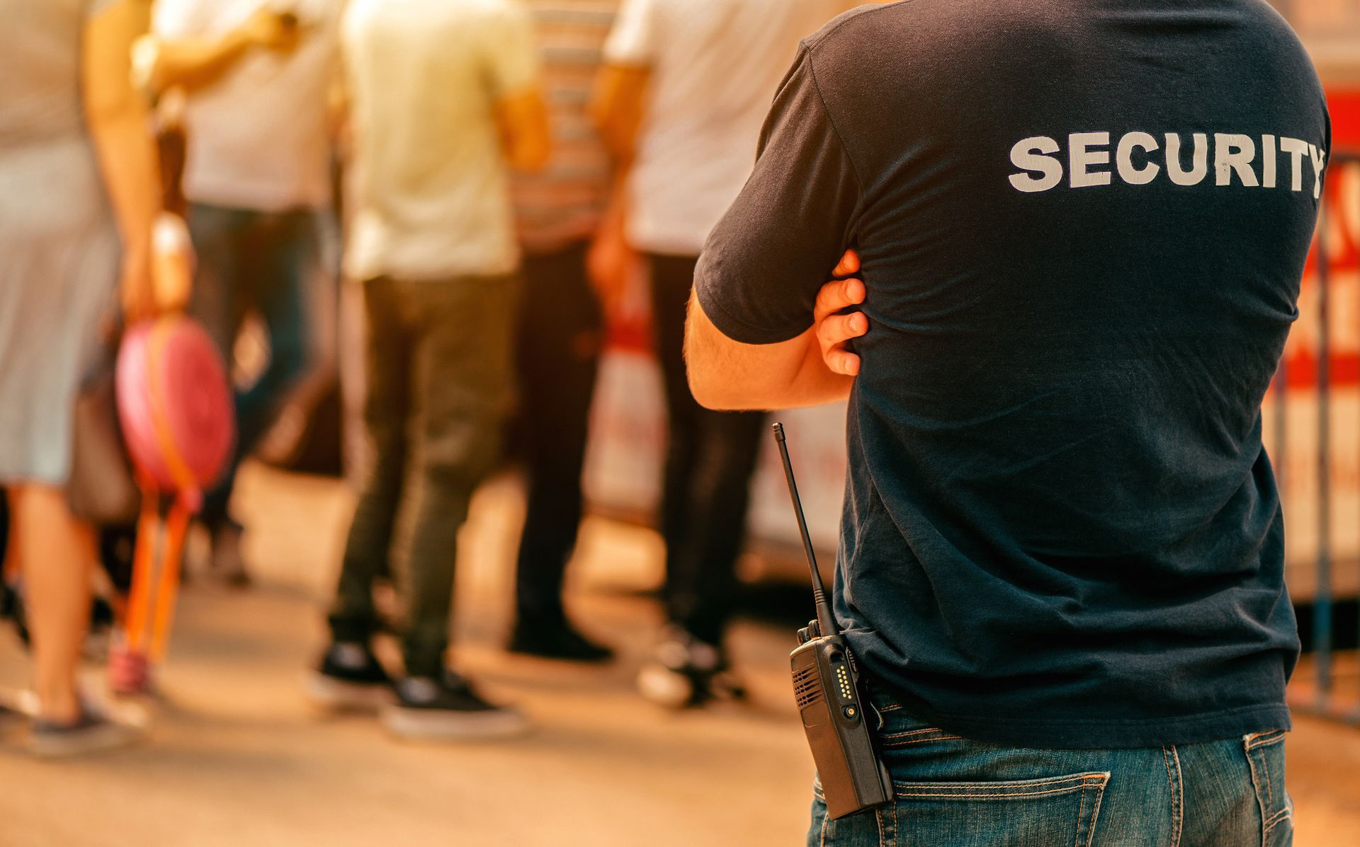 A security guard is standing in front of a crowd of people.