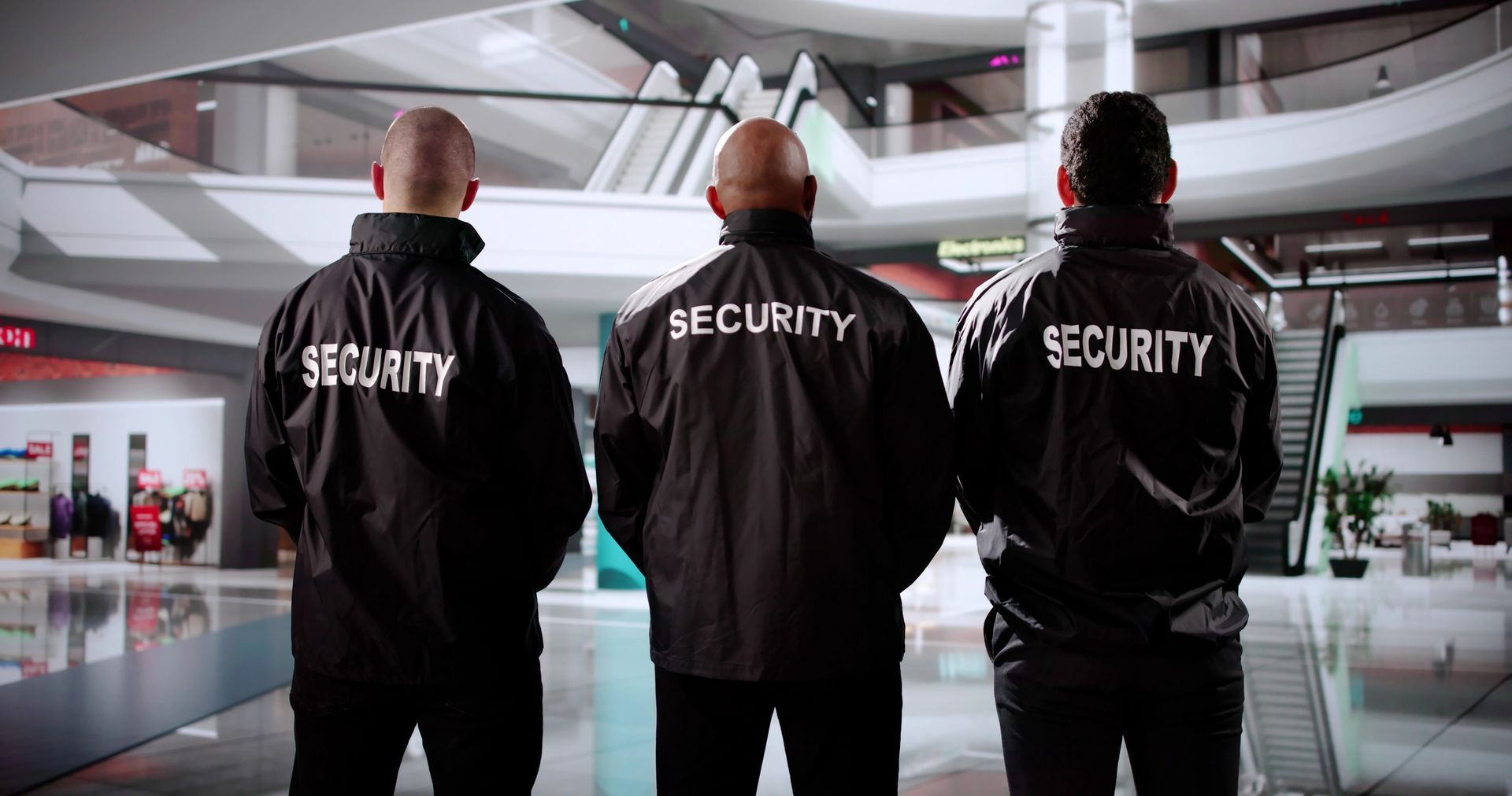 Three security guards are standing next to each other in a mall.