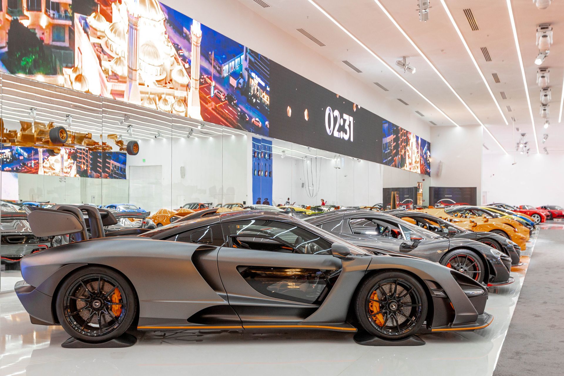 a row of sports cars are parked in a large room .