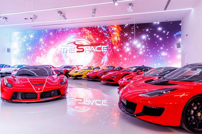 two red sports cars are parked in front of a building that says the space