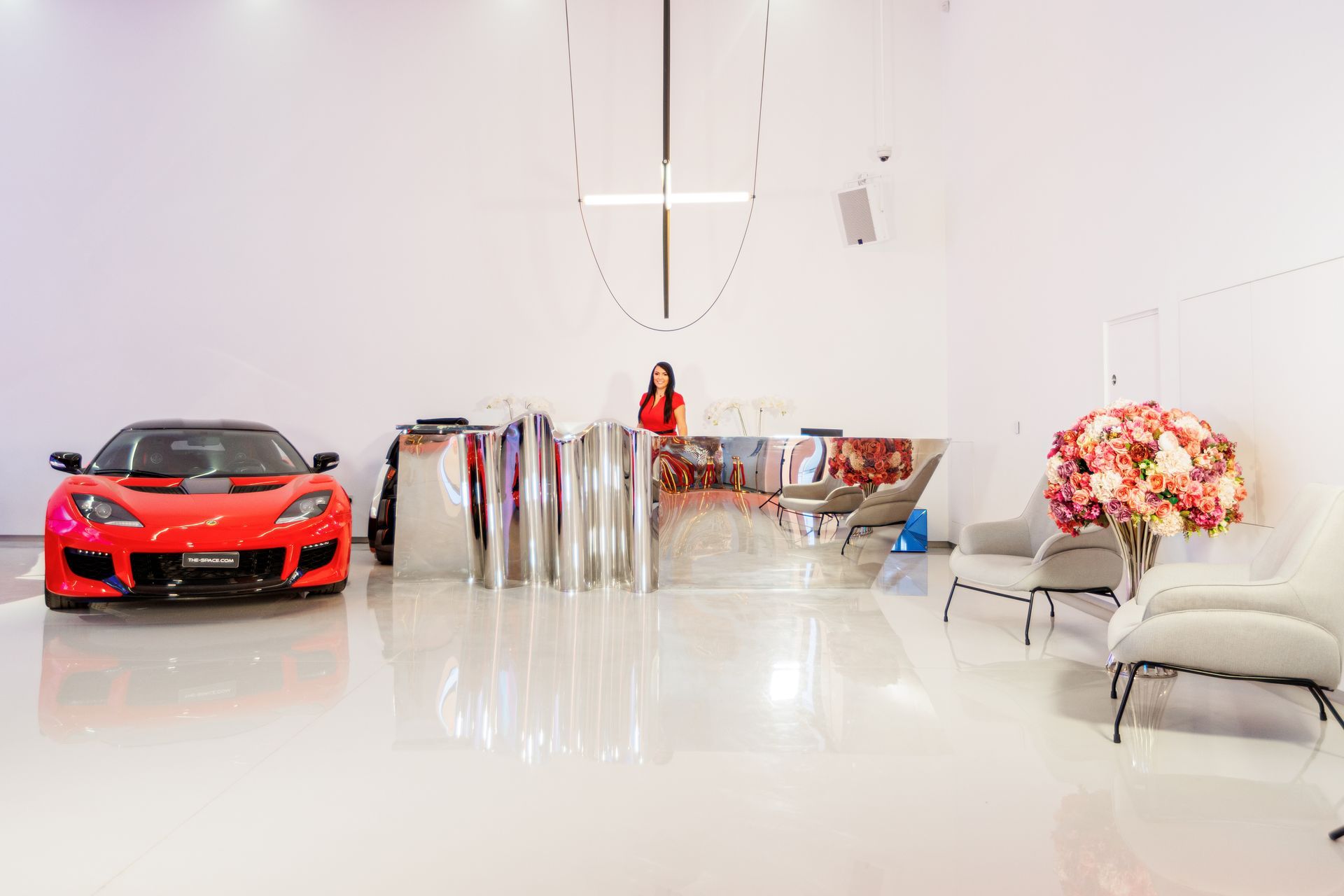 a woman is standing next to a red sports car in a living room .