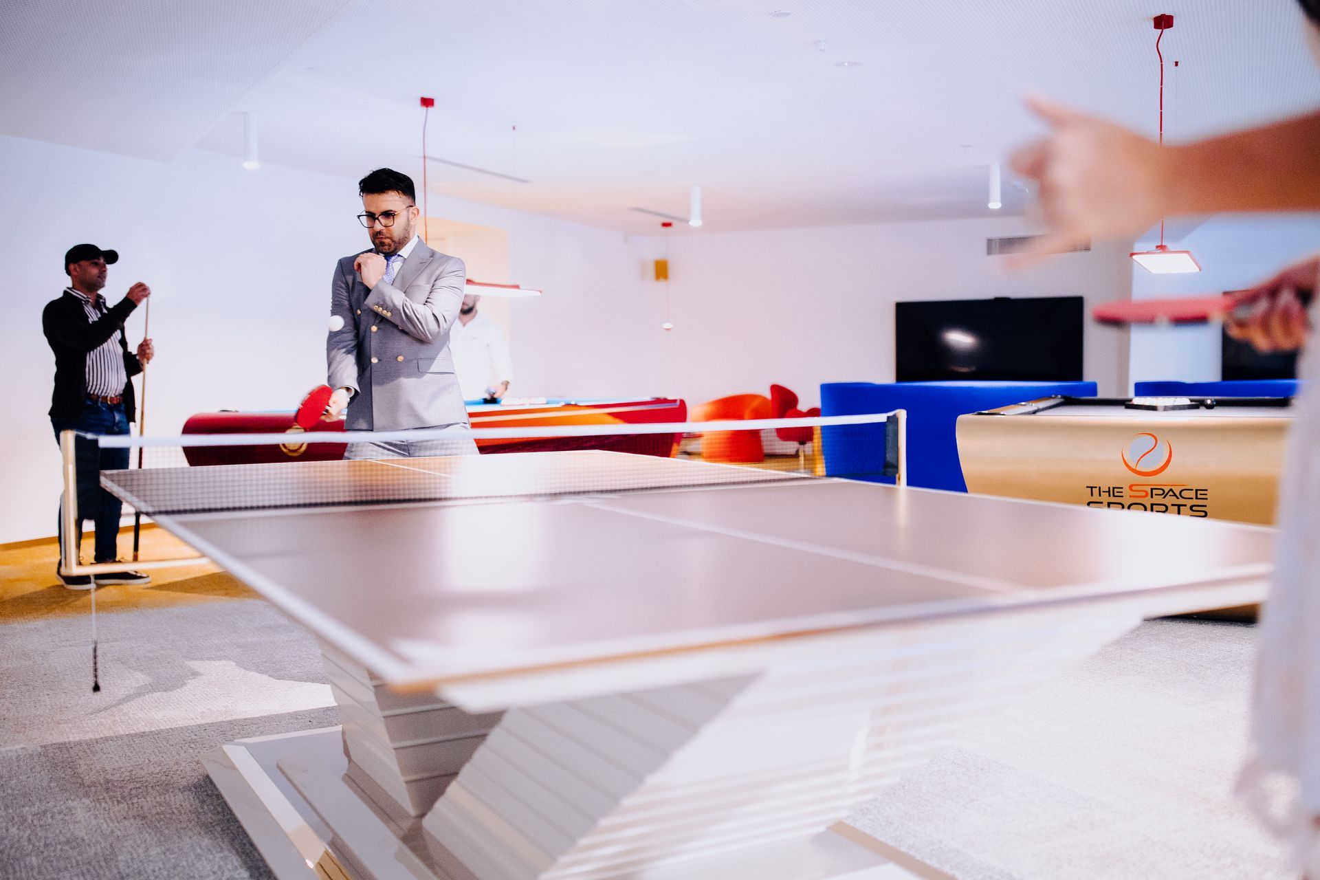 a group of people are playing ping pong in a room .