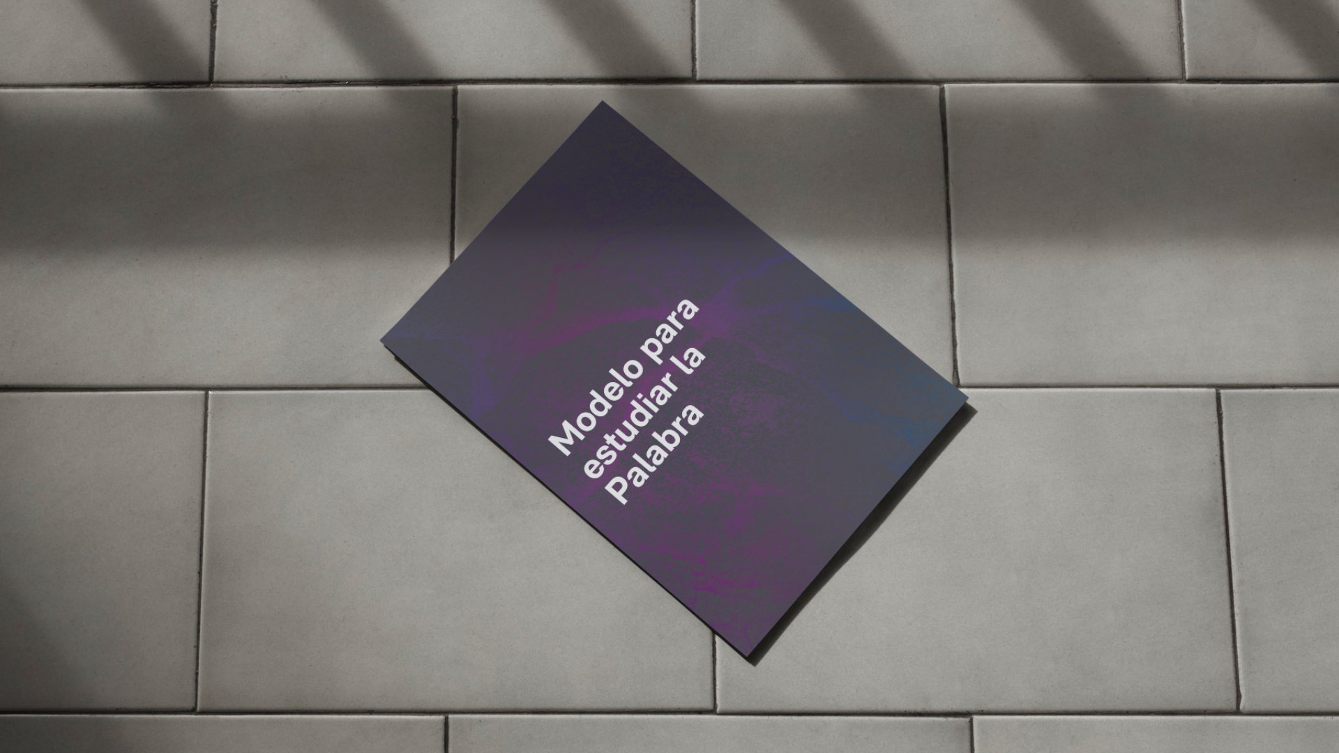 Un libro morado yace sobre un suelo de baldosas.