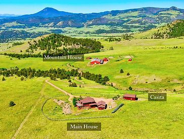 an aerial view of a mountain house in the middle of a grassy field .