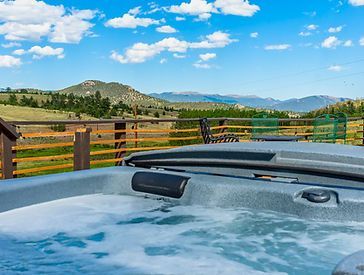 a hot tub on a deck with mountains in the background .