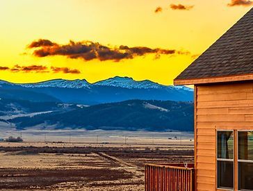 a house with a view of a mountain range at sunset .