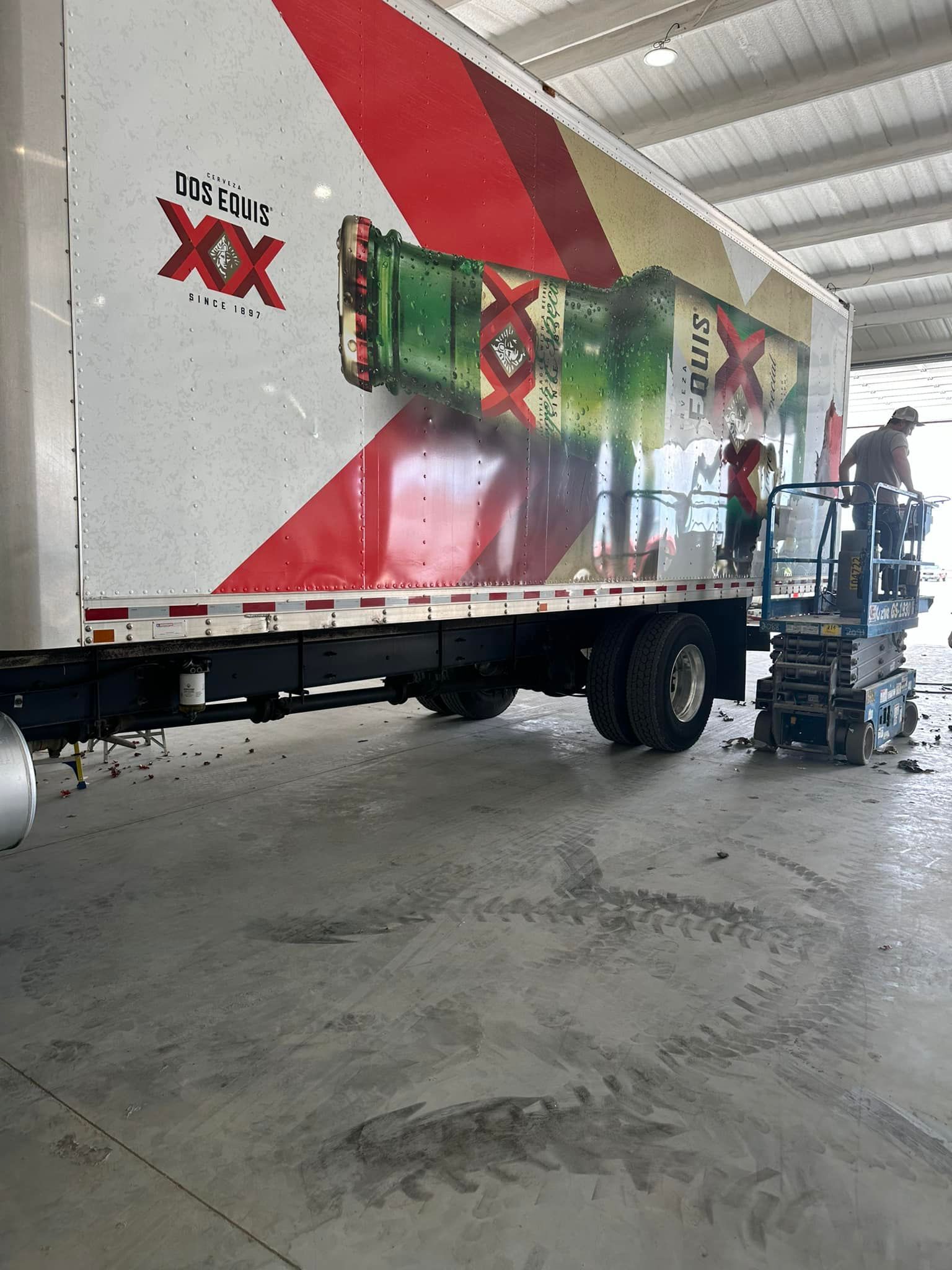 A truck with a bottle of beer on the side is parked in a garage.