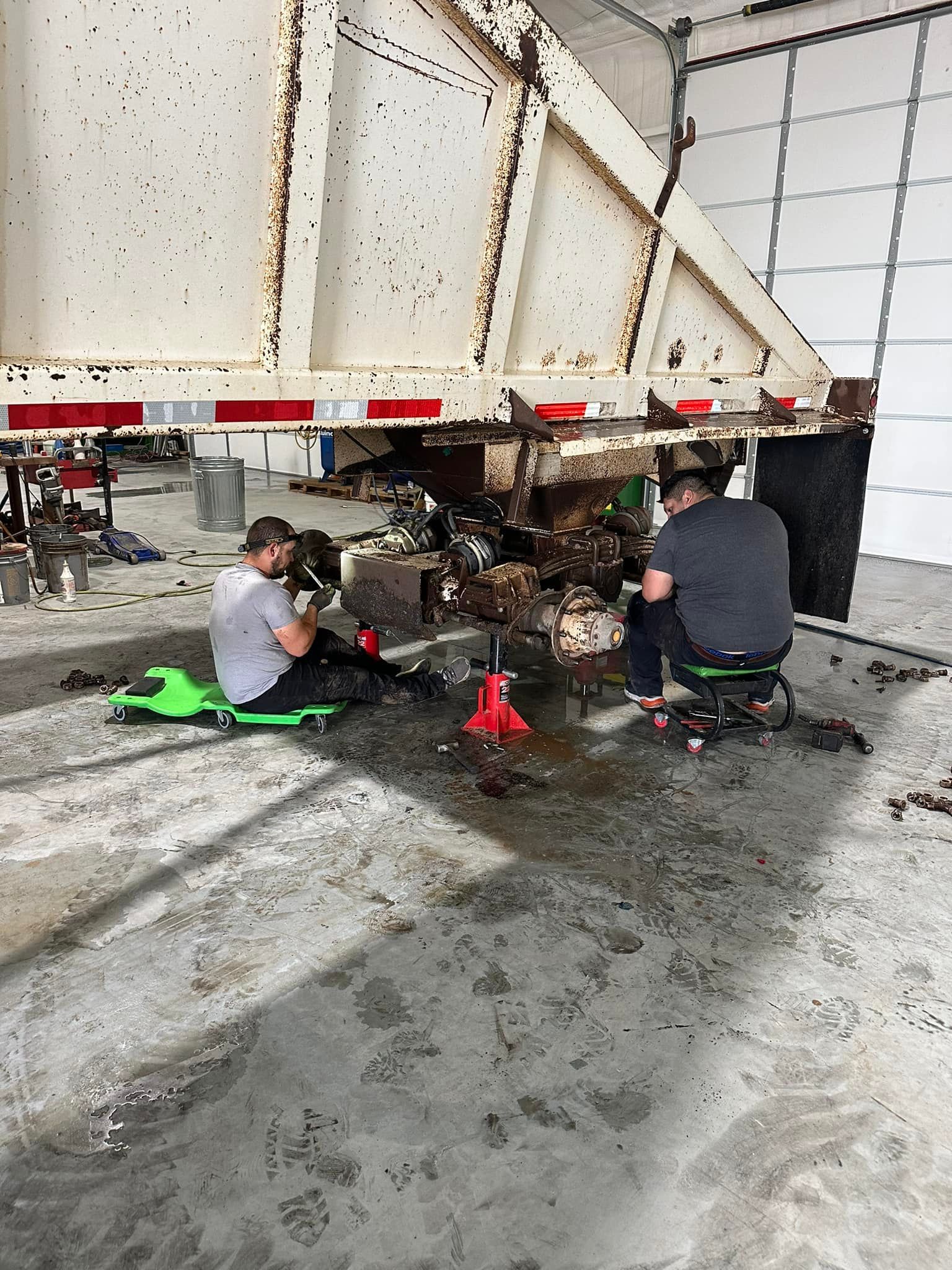 Two men are working on a trailer in a garage.