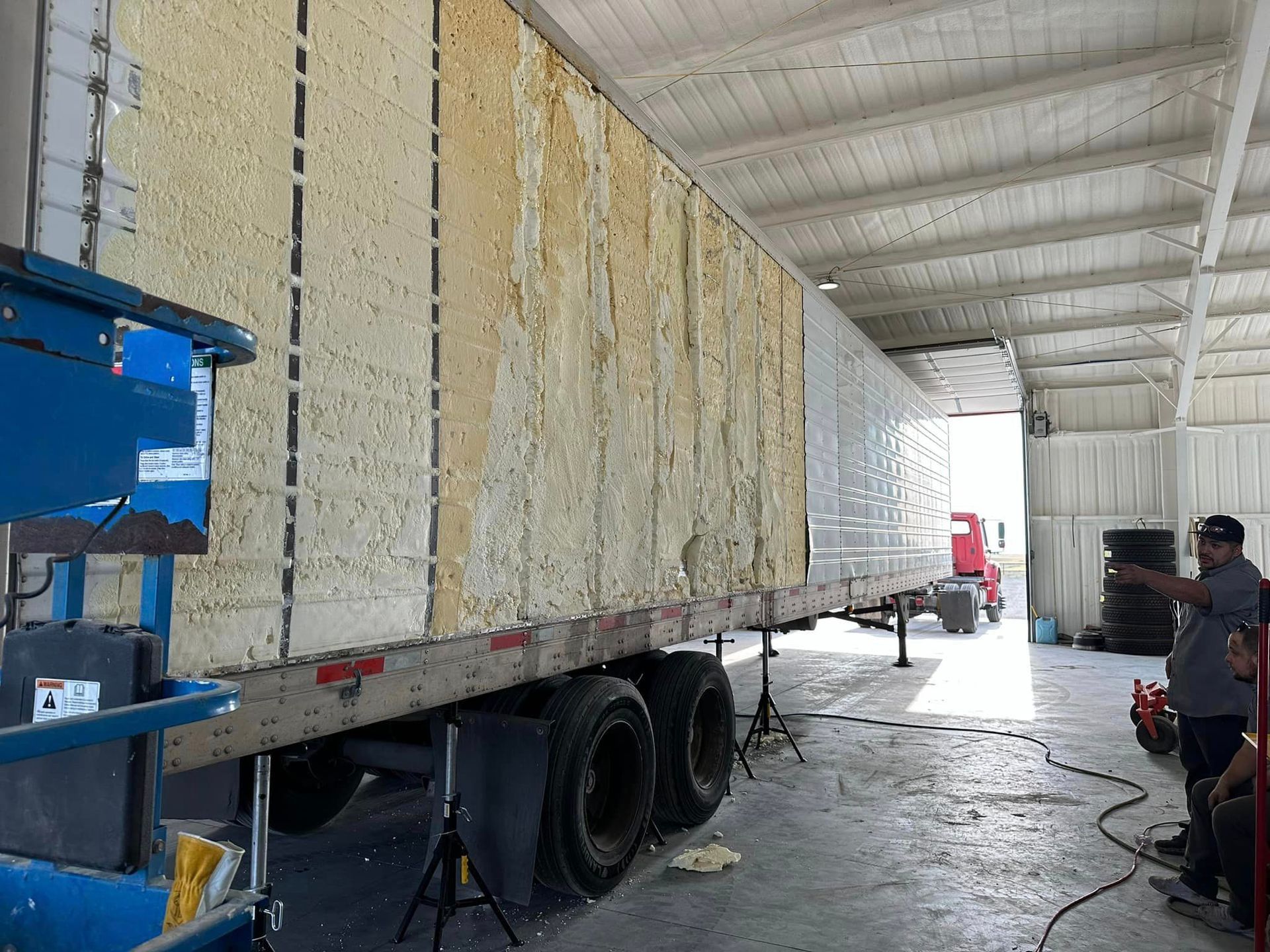 A man is working on a semi truck in a garage.