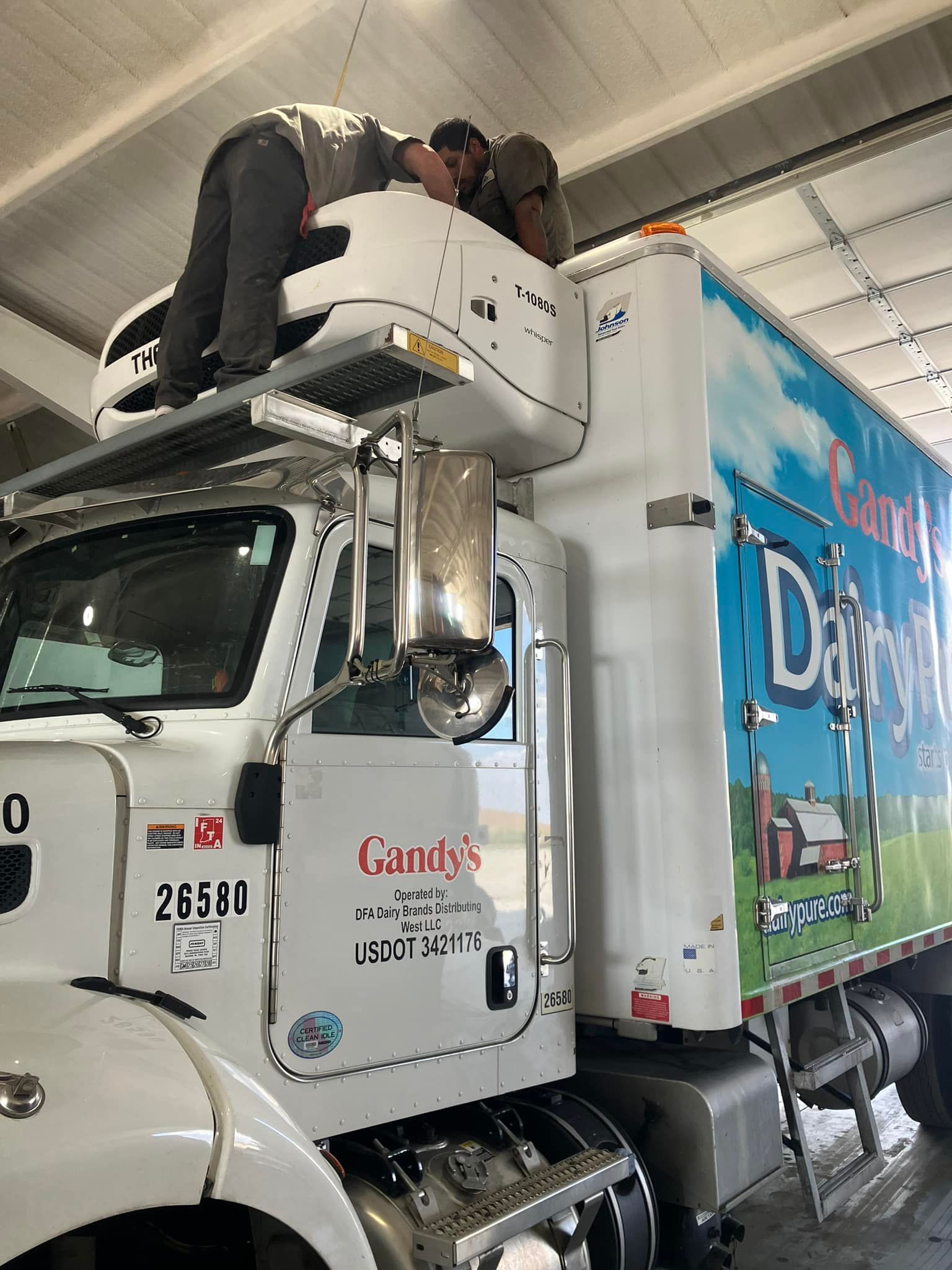 A man is working on the roof of a semi truck.