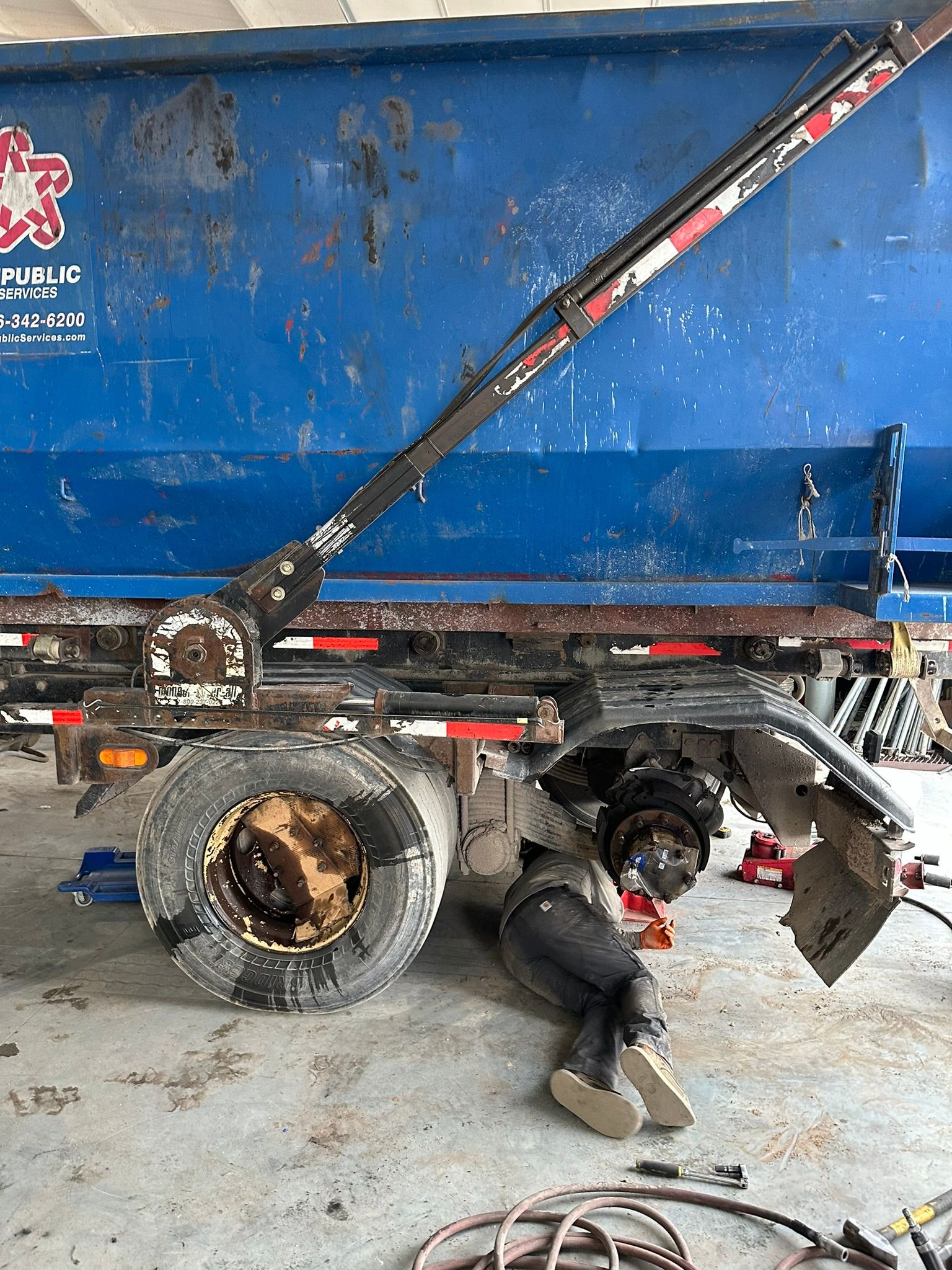 A man is working on a dump truck in a garage.