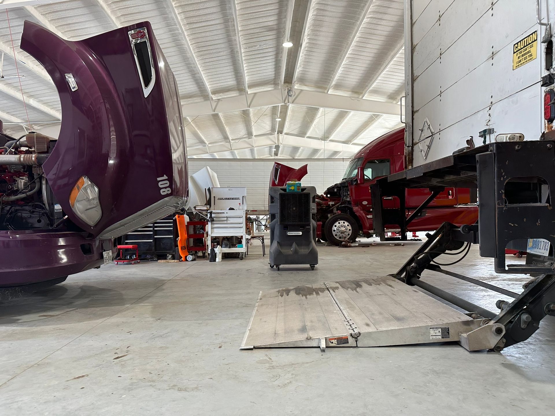 A man is holding a wrench in front of a truck.