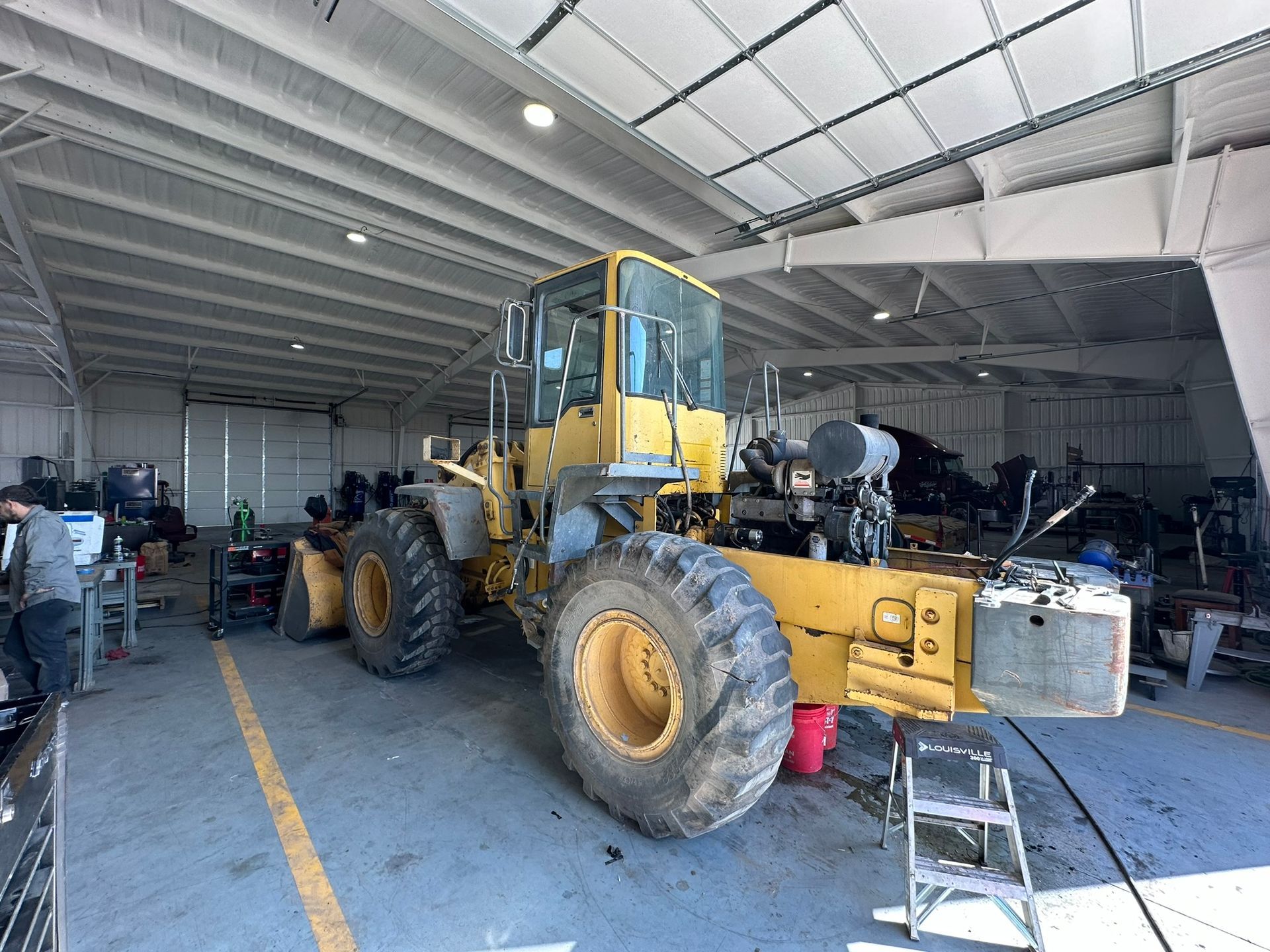 A large yellow tractor is parked in a garage.
