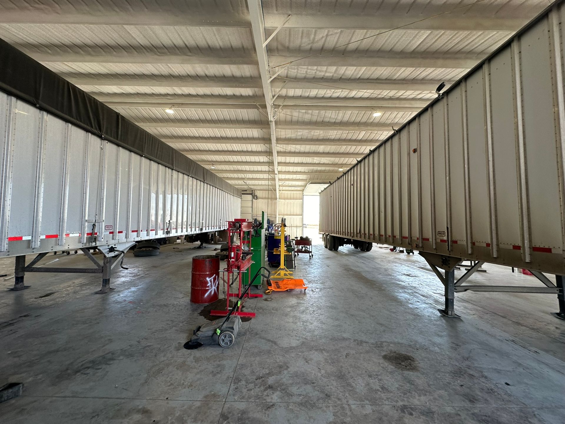 A warehouse filled with trucks and trailers being worked on.