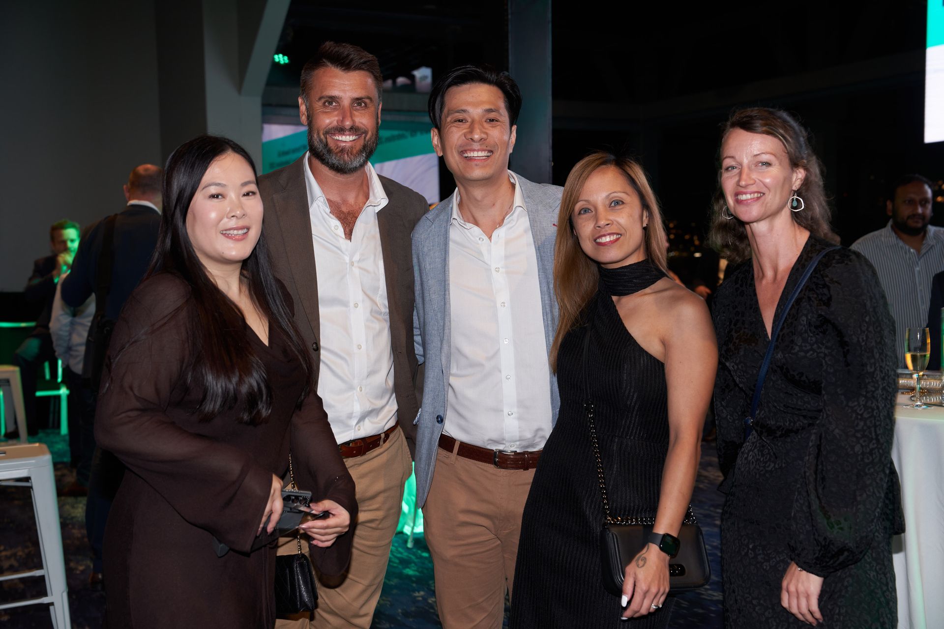 Five people smiling, posing together indoors at an event.