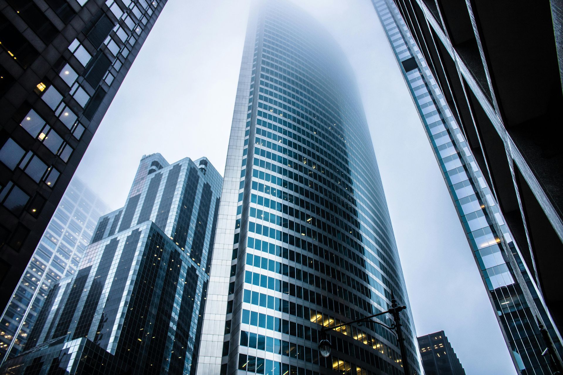 Looking up at a tall building in a city on a foggy day.