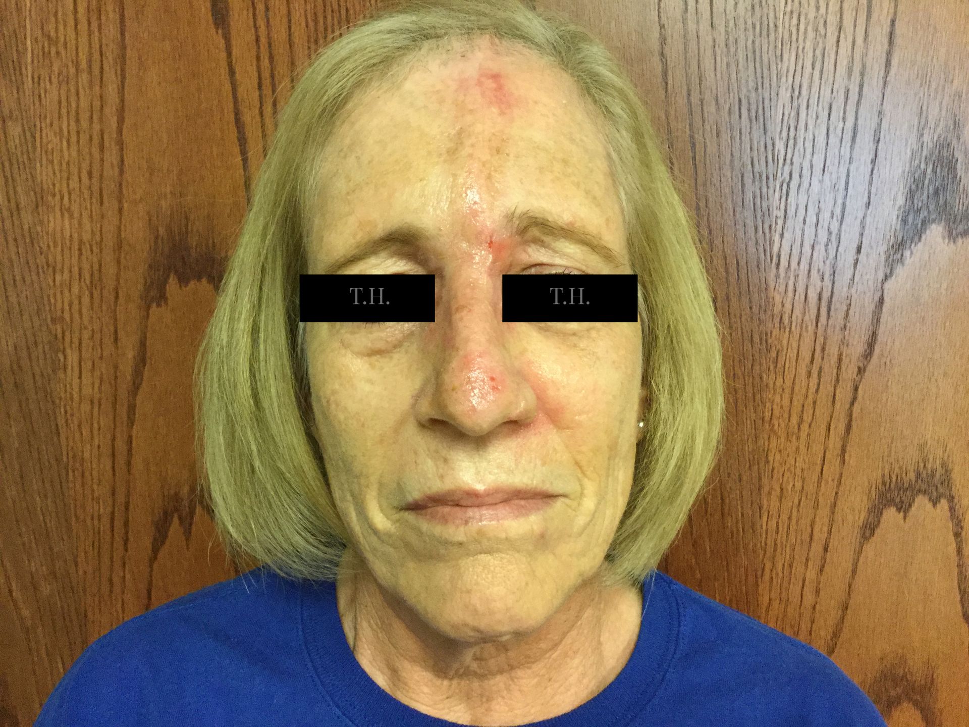 A woman is smiling in a room with a picture on the wall behind her.