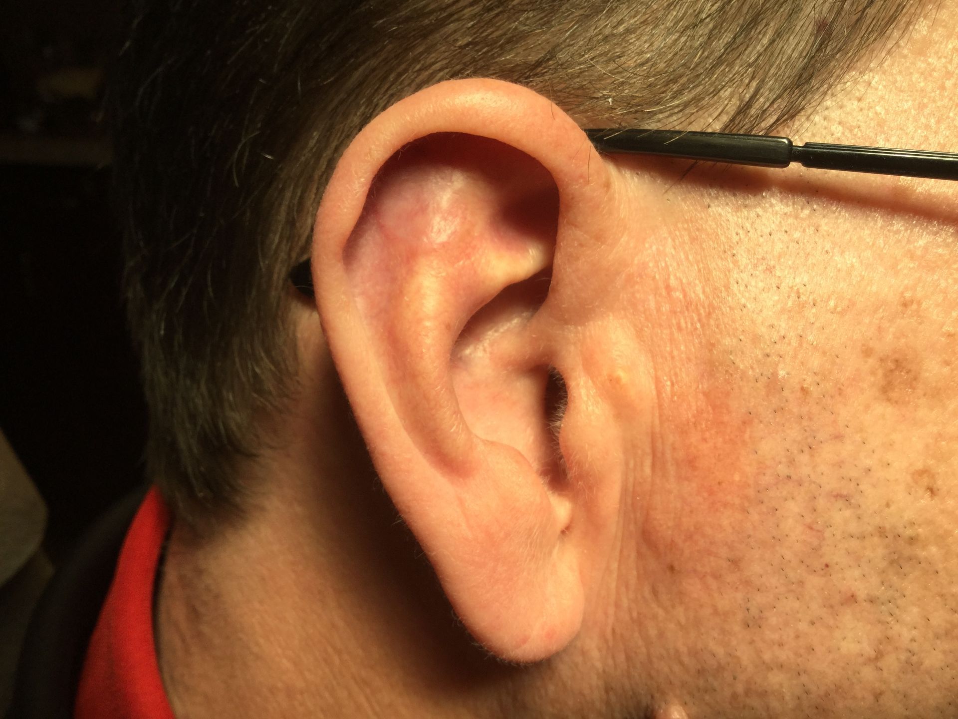 A close up of a man 's ear with glasses on