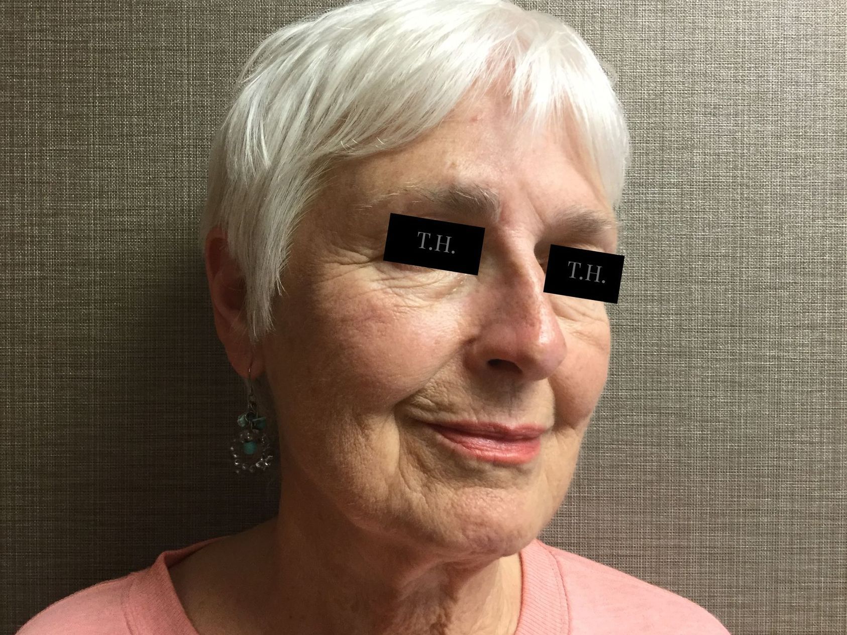 A close up of an older woman 's face with a pink shirt on.