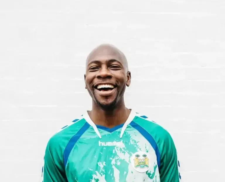 A man wearing a green hummel shirt is smiling