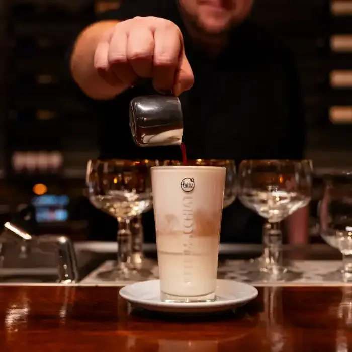 een man schenkt een drankje in een glas met het woord koffie erop