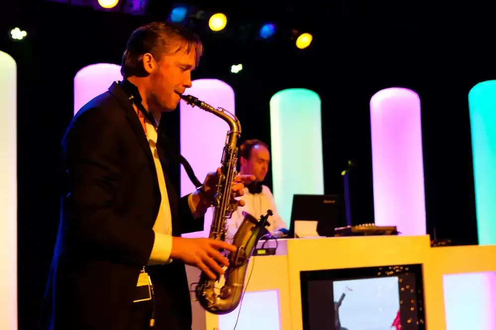 een man in pak speelt saxofoon voor een dj.