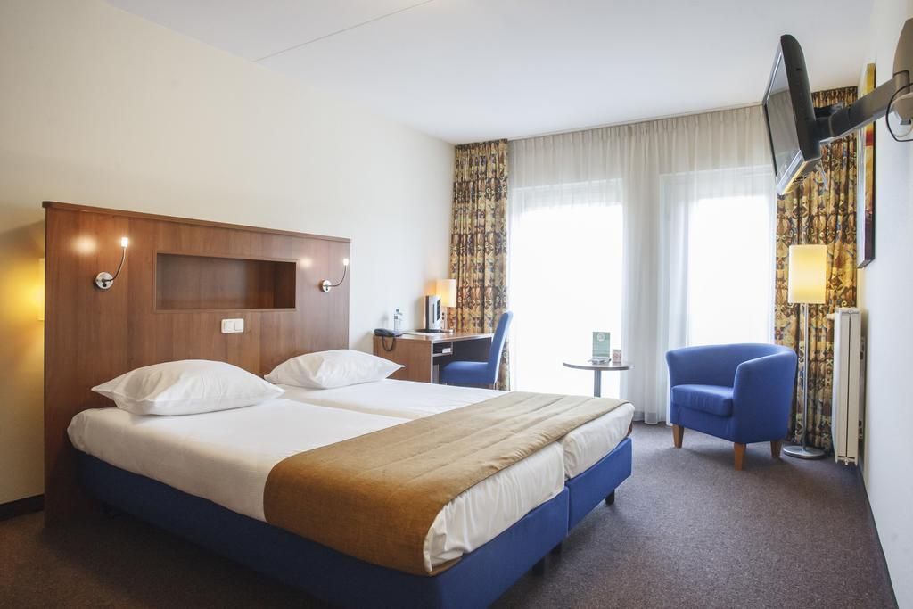een hotelkamer met twee bedden en een blauwe stoel