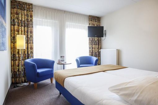 een hotelkamer met een bed twee stoelen en een televisie