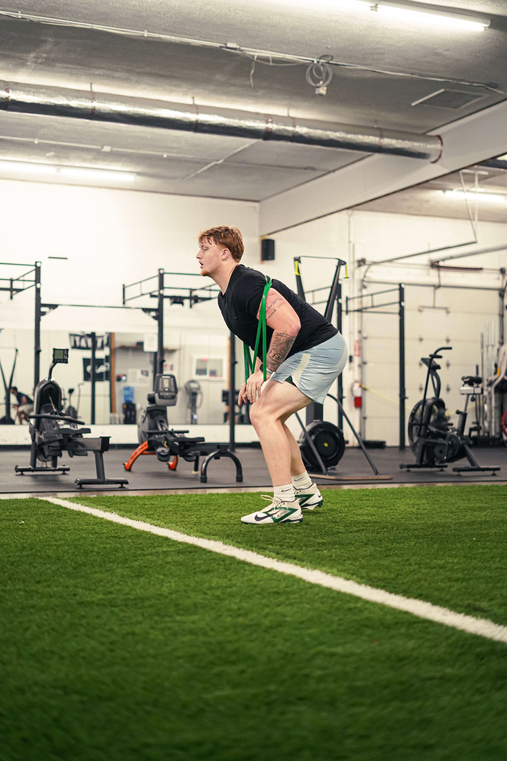 Man in athletic stance with band, gym.
