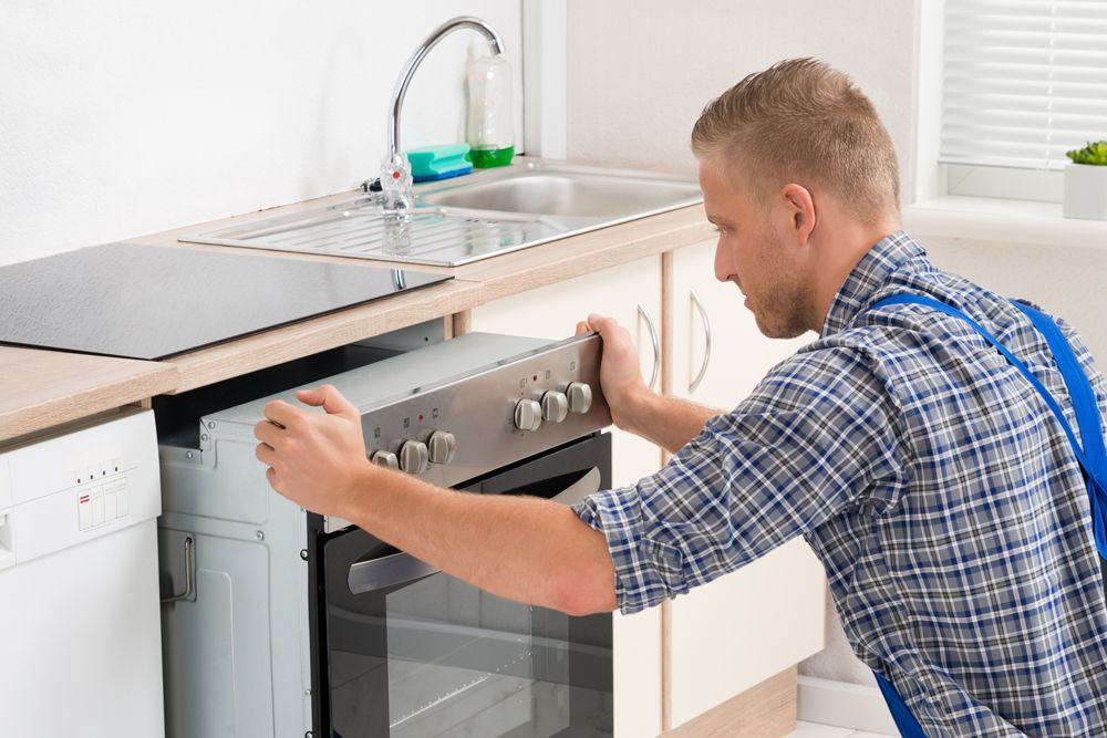 a man is fixing an oven in a kitchen