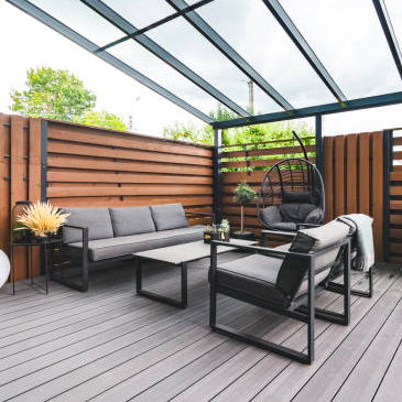 A patio with a couch , chairs , and a glass roof.