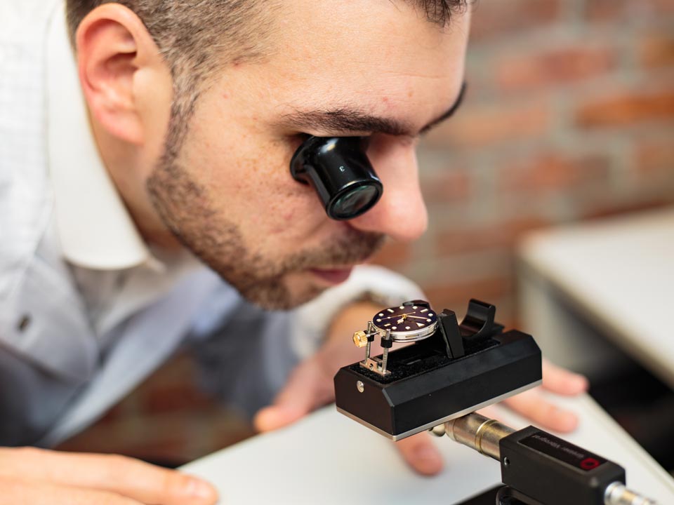 man wearing a magnifying lens and looking at the watch