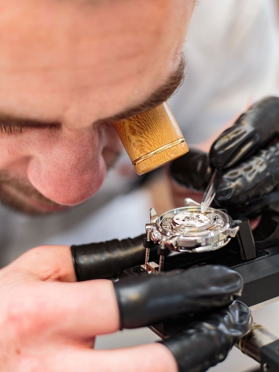 man closely looking at the watch during repair