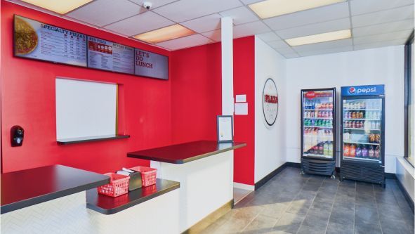 The inside of a fast food restaurant with red walls and a counter.