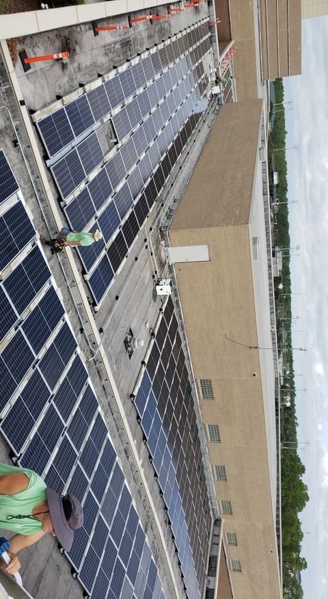 A man is standing on the roof of a building with solar panels on it.