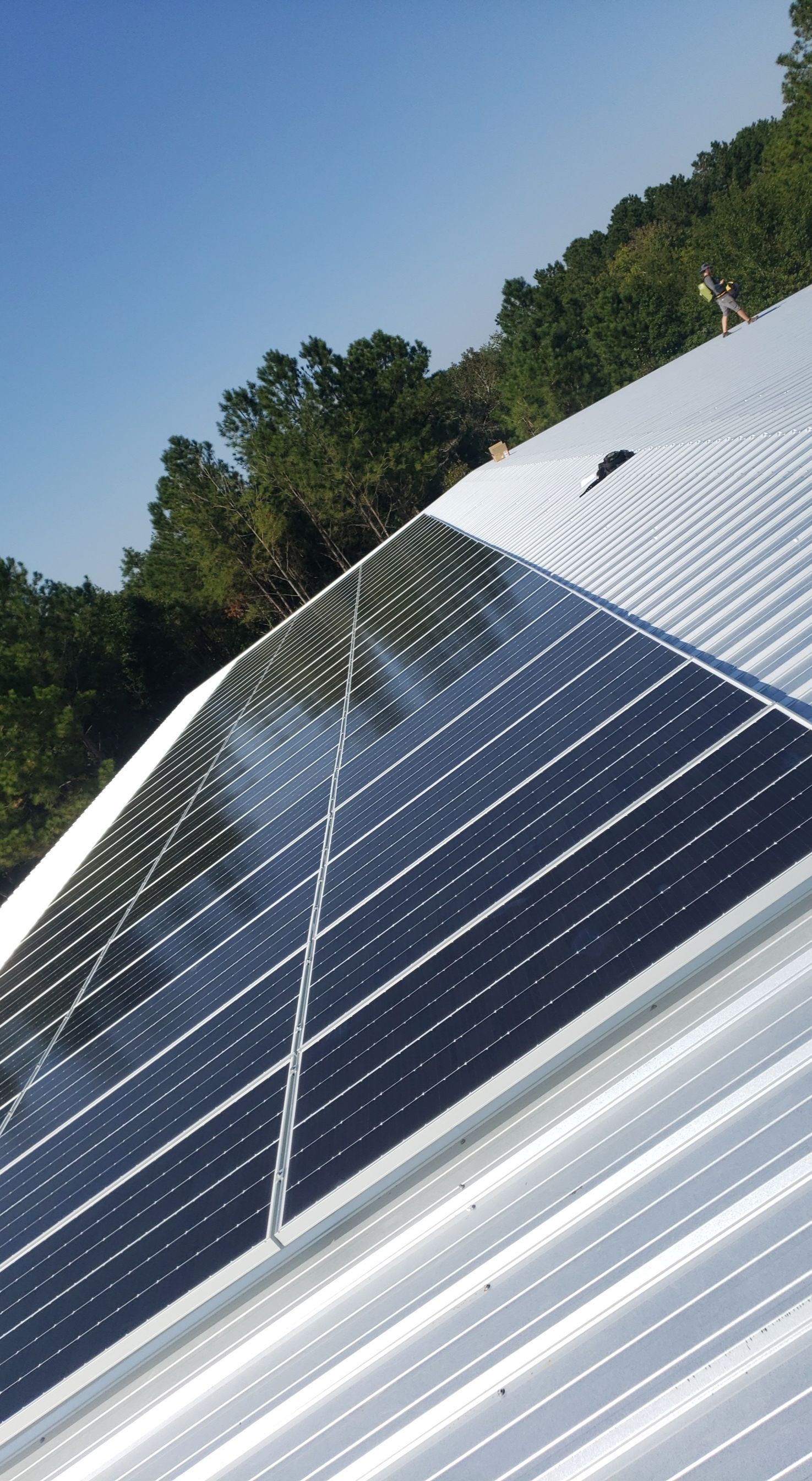 There are many solar panels on the roof of a building.