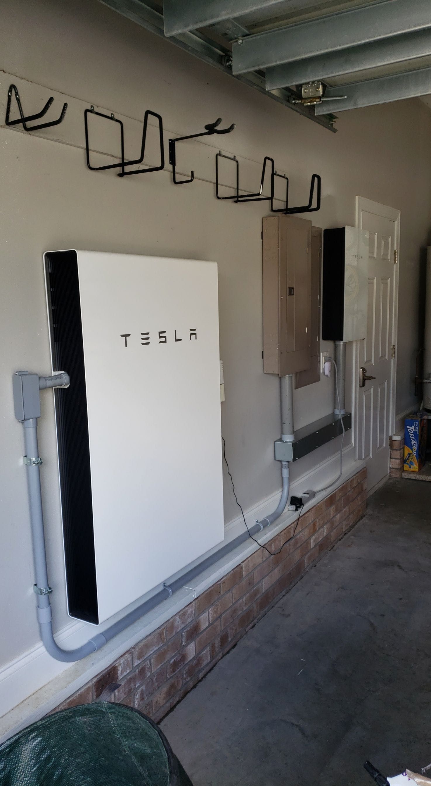 A tesla solar panel is mounted on the wall of a garage.