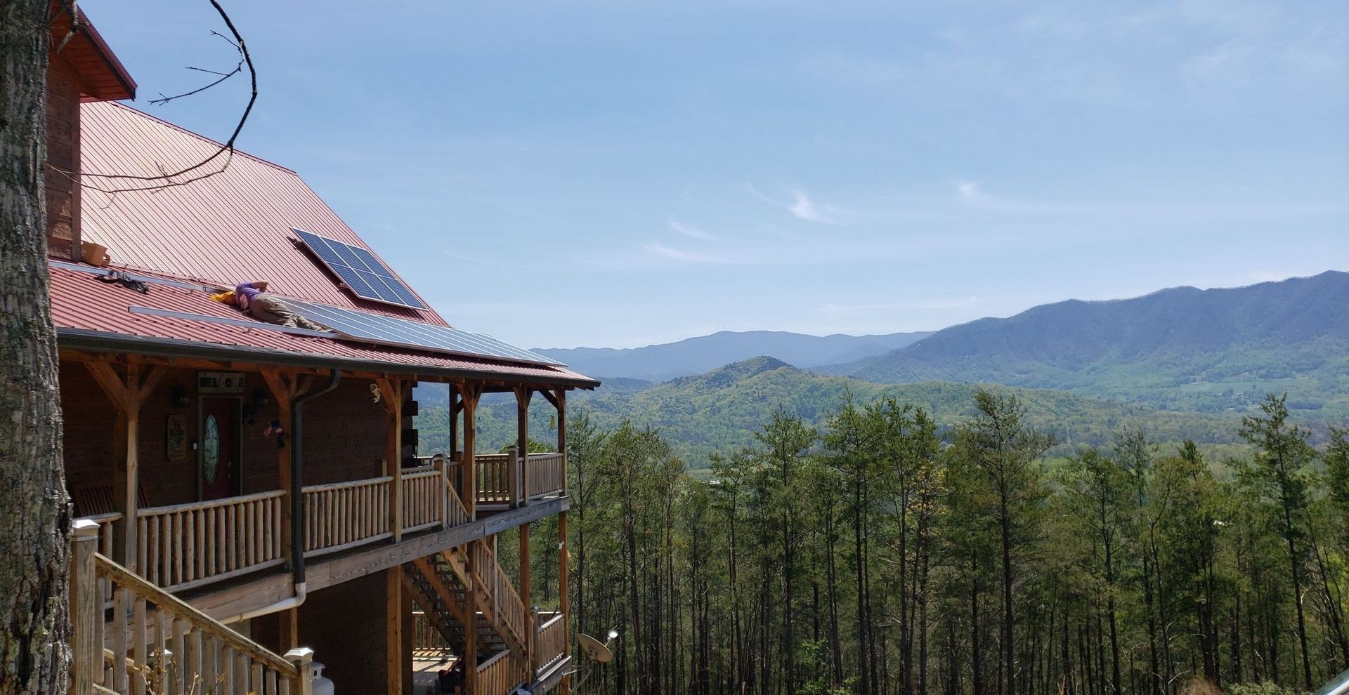 A large log cabin with a view of a forest and mountains.