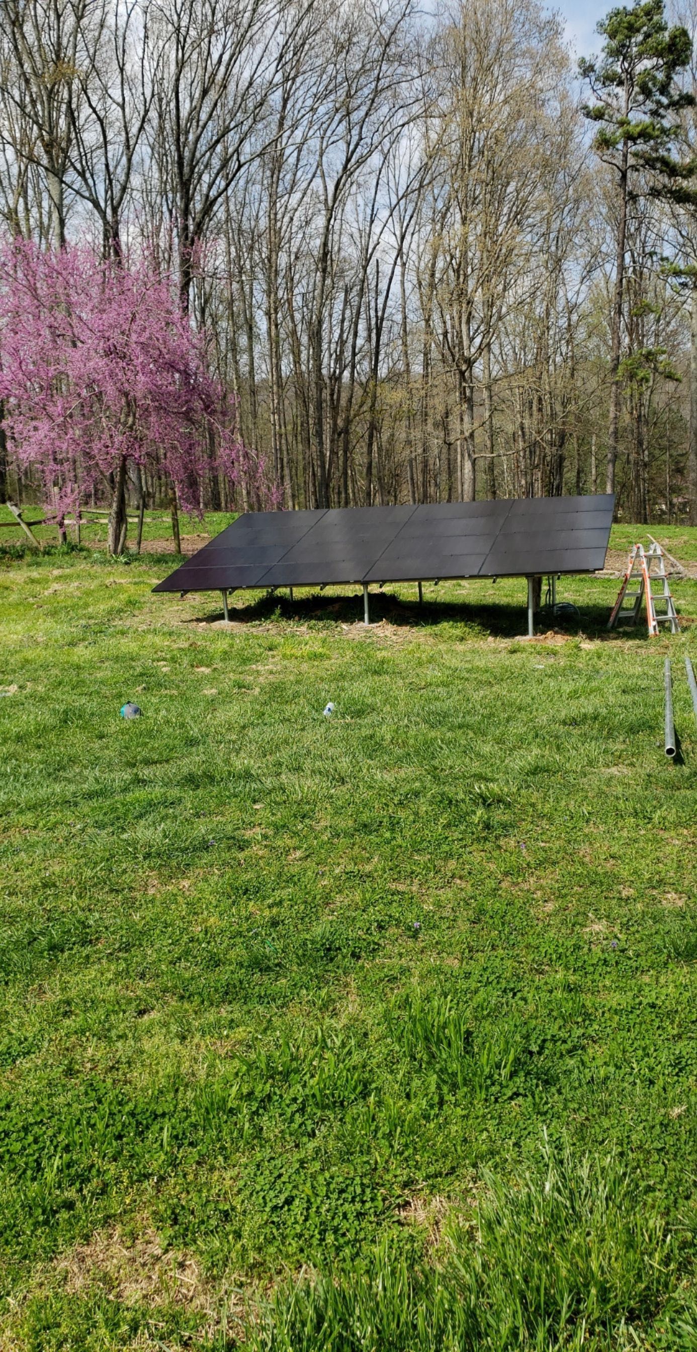 A solar panel is sitting in the middle of a grassy field.