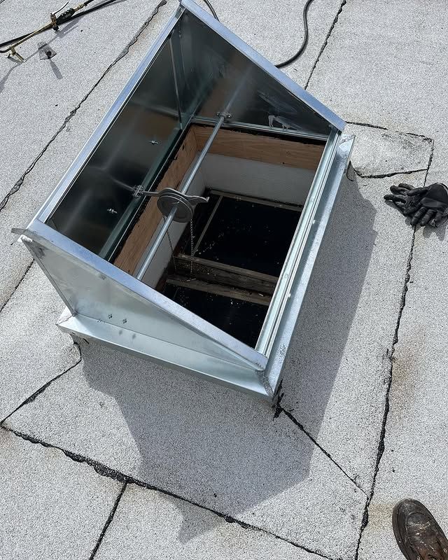 A metal box is sitting on top of a roof with a hole in it.