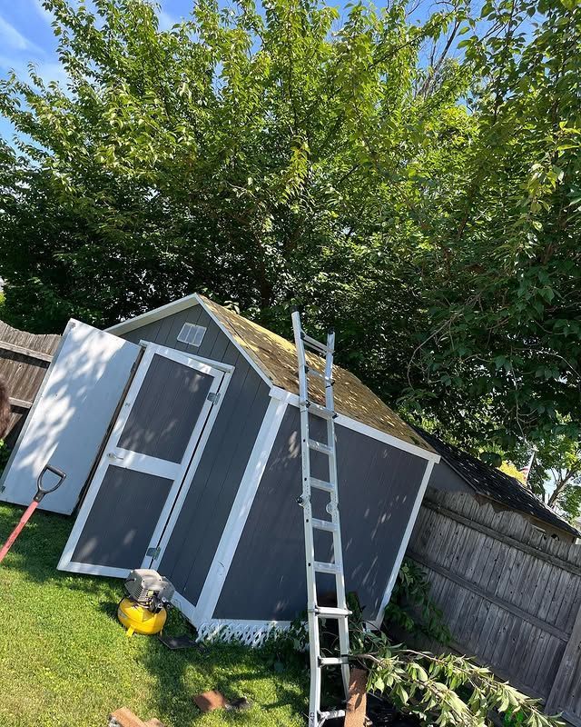 A ladder is sitting on top of a shed in a backyard.
