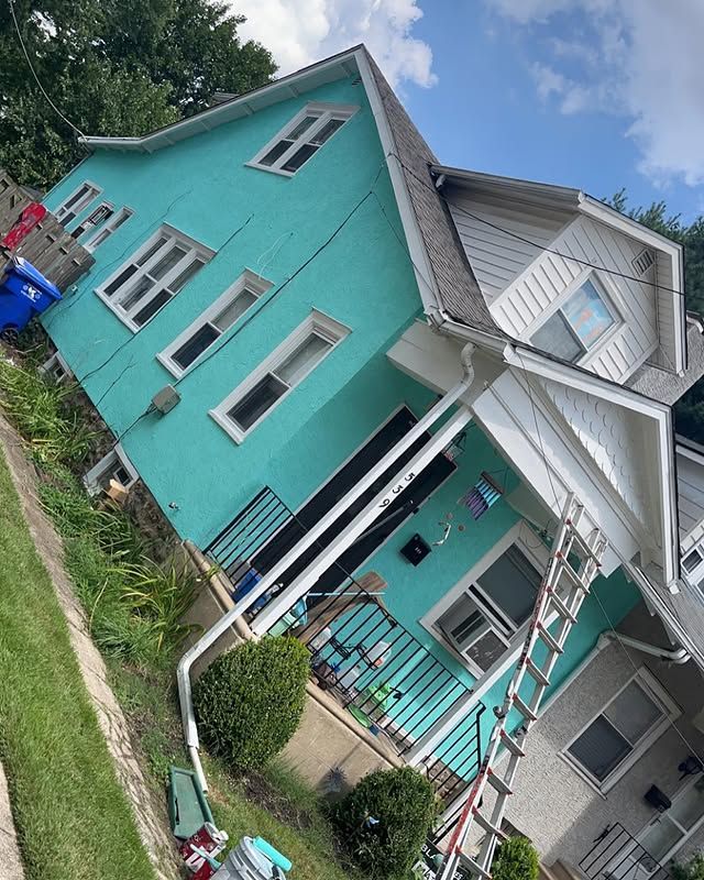 A blue and white house with a ladder in front of it.