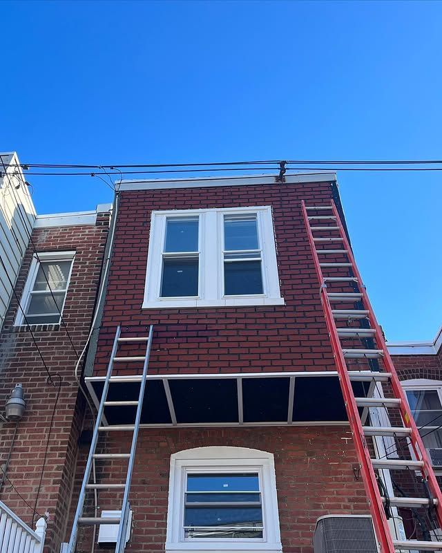 A ladder is sitting on the side of a brick building.