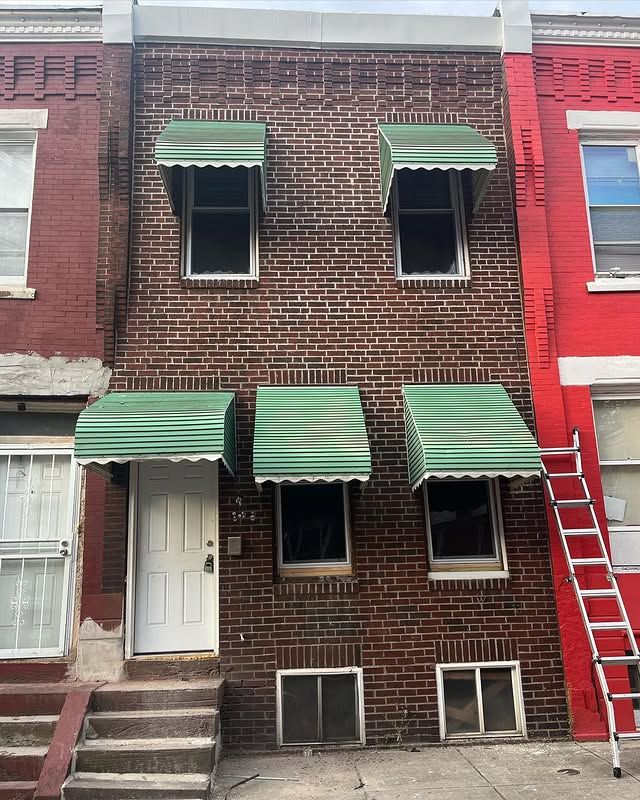 A red brick building with green awnings on the windows
