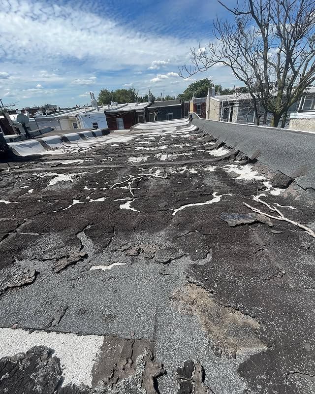 A roof with a lot of damage on it and a tree in the background.